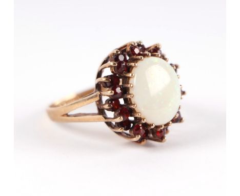 A 9ct gold opal and garnet cluster ring with central opal surrounded by a halo of garnets, approx UK size 'N', 5.3g.
