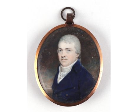 An early 19th century yellow metal mounted oval portrait miniature on ivory depicting a gentleman wearing a blue coat with me