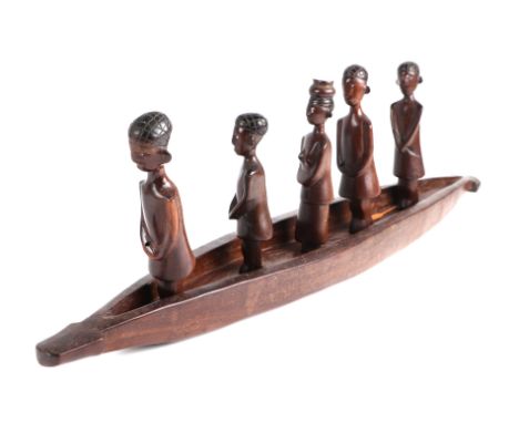 An African carved hardwood figural group depicting five standing figures in a canoe, 72cms long.