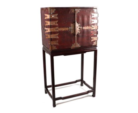 A Chinese leather covered trunk with copper reinforced strap work, the twin doors opening to reveal a red lacquered interior 