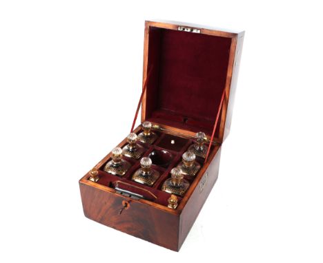 An early 19th century figured mahogany travelling decanter box with fitted interior containing seven square form gilt decorat