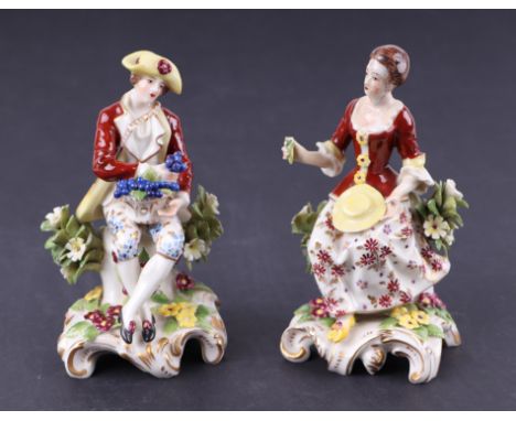 A pair of Chelsea style porcelain figures depicting a seated lady and gentleman, each approx 13cms high (2).