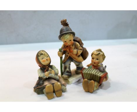 Three Goebel / Hummel figures to include girl feeding birds, a cello player and a concertina player (3)