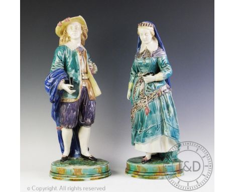 A pair of Majolica figures, early 20th century, modelled as an 18th century couple each holding a bible, 48cm and 51cm high (