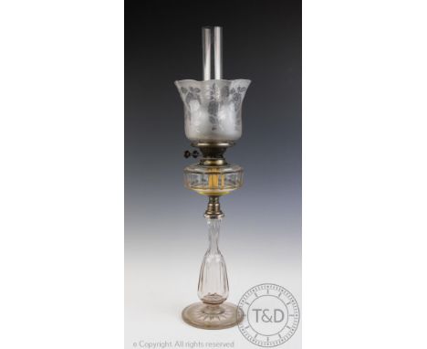 A Victorian glass oil lamp, the clear glass faceted reservoir above a hollow baluster stem and star cut base, 73cm high overa