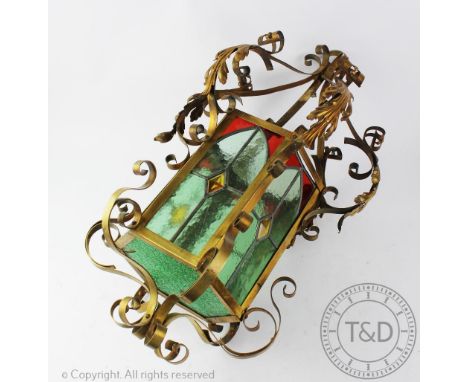 An Arts and Crafts type brass hexagonal hall lantern, with stained glass panels and scrolling detailing, 66cm high CONDITION 