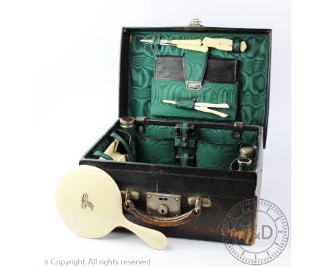 An Edwardian travelling dressing case, enclosing assorted ivorine dressing accessories including, combs, brushes, a mirror, m