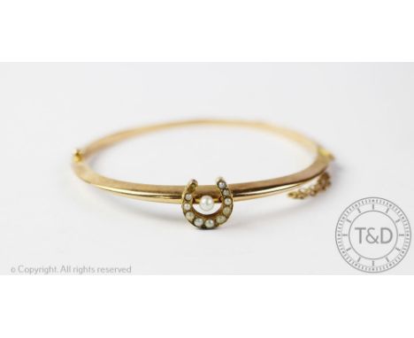 A seed pearl set horseshoe bangle, the hinged bangle set with a horseshoe with graduated split seed pearls, all set in yellow