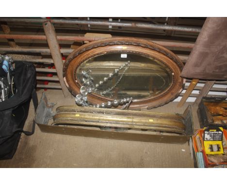 An oval bevel edged wall mirror in carved wooden frame, hanging four branch candelabra and two brass fire fenders