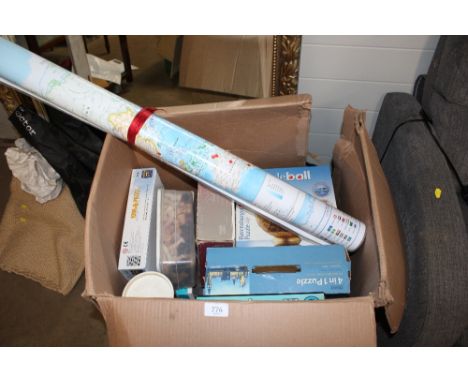 A large box containing various puzzles, chess pieces, rolled map etc 