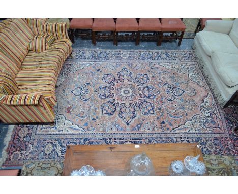 An old Persian Heriz carpet, the large centre medallion design on pale rose ground, 3.48 x 2.50 mColours faded, some areas of