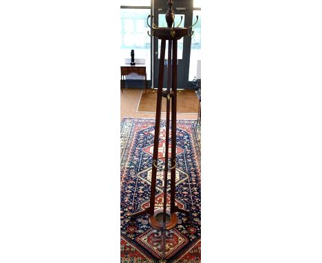 A late 19th/20th century brass fitted mahogany railway cloak stand, the top revolving over a central drip tray, bears oval pl