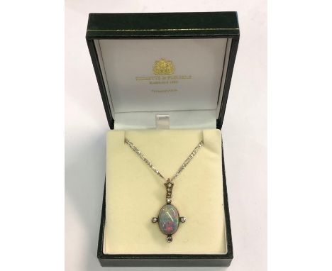 An Arts and Crafts style pendant, the oval black opal in yellow gold collet mount with four old cut diamonds, suspended from 