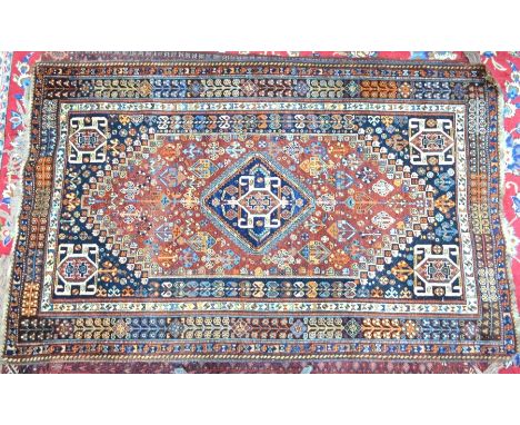 A South West Persian Shiraz carpet circa 1950s, the central navy diamond medallion on a terracotta ground with floral motif w