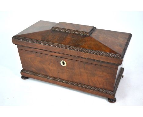 A Regency flame mahogany sarcophagus form tea caddy, the interior with two boxes centred by a circular well, raised on squat 