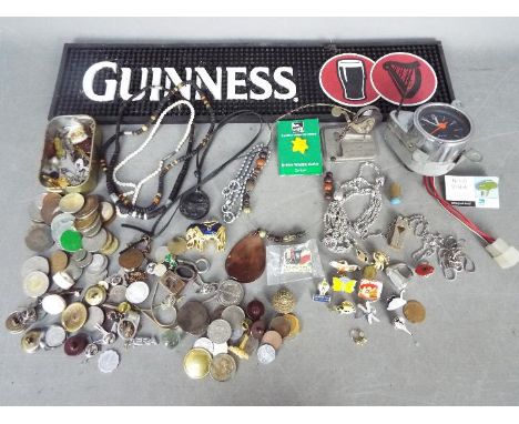 A mixed lot to include a Guinness bar mat, Japanese dashboard clock, coins, costume jewellery, pin badges and similar.Lot des