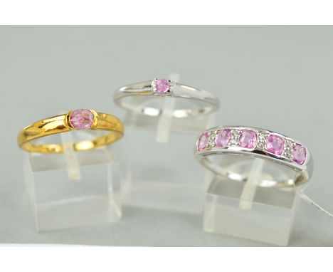 THREE 9CT GOLD PINK SAPPHIRE DRESS RINGS to include a pink and white sapphire half hoop, ring size V, a small single stone pi