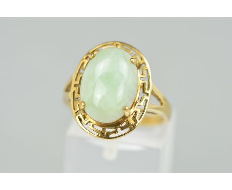 A 9CT GOLD JADE RING, the oval jade cabochon within an open Greek key surround to the bifurcated shoulders, with foreign assa