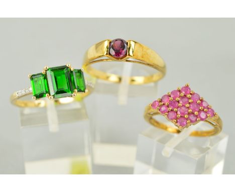 THREE GOLD GEM SET RINGS to include a 9ct gold circular stone garnet ring, ring size U, a 9ct gold treated ruby cluster ring,