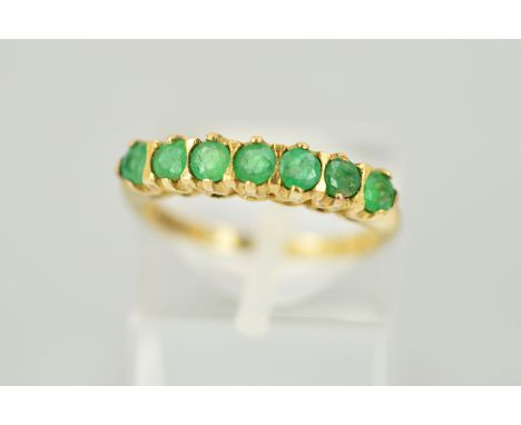 A 9CT GOLD SEVEN STONE EMERALD RING designed as a row of circular emeralds with a 9ct hallmark for London 1993, ring size K, 