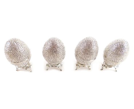 Four Swarovski decorative eggs, each hinged with plain enamel interiors, on stands, in outer yellow boxes, each egg 5cm high.