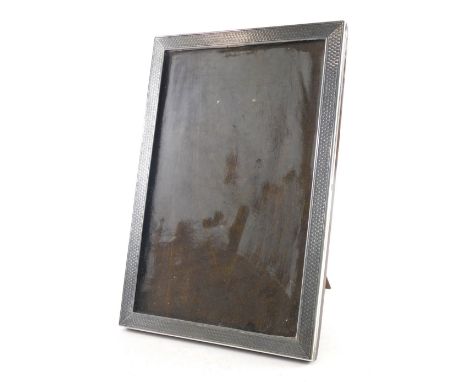 A George V silver photograph frame, by Sanders and Mackenzie, of rectangular form, partially engine turned, with oak easel ba