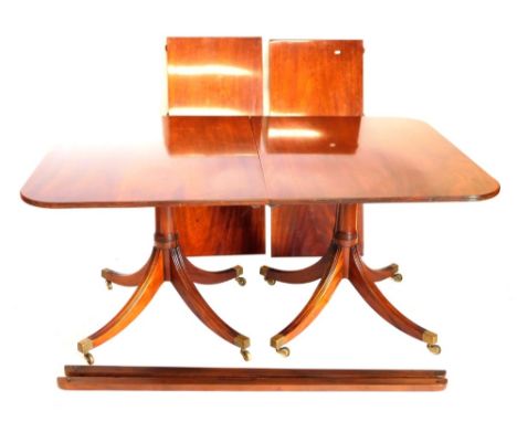 A Regency style mahogany extending dining two pillar dining table, the rectangular top with rounded corners and a reeded edge