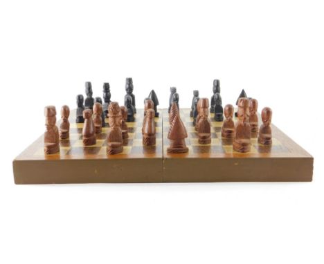 A carved wooden chess set and folding board, king 7cm high approx.  Upon initial inspection marks wear and losses, 16g each c