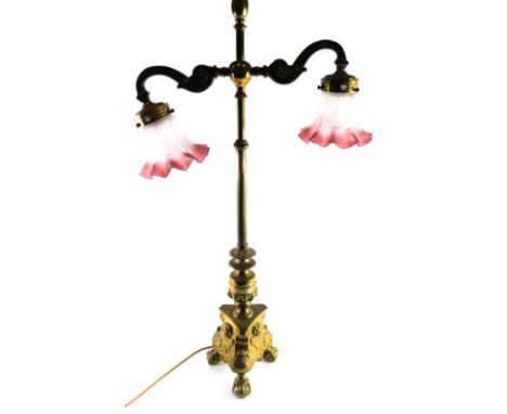 A 20thC two branch brass table lamp, with cylindrical reeded section and upper S scroll sections holding frosted pink, white 