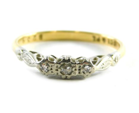 A 18ct gold and platinum diamond three stone ring, set with three tiny diamonds in illusion setting on a yellow metal band, r