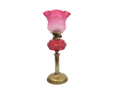 A 19th century brass and cranberry glass oil lamp: the large crimped shade above a faceted cranberry glass reservoir and bras