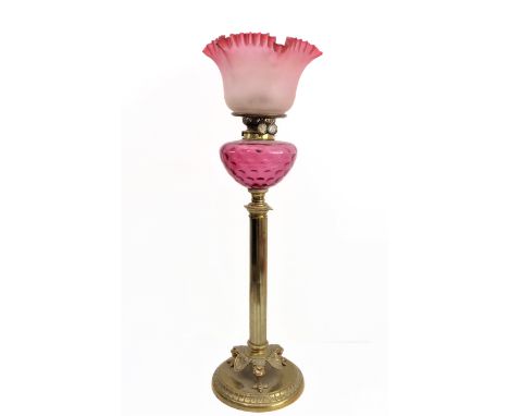A 19th century brass and cranberry glass oil lamp: the crimped edge shade above a cranberry glass reservoir and fluted stem l