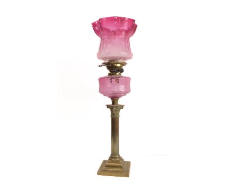 A 19th century brass and cranberry glass oil lamp: the crimped-edge etched shade above a flat circular light cranberry glass 