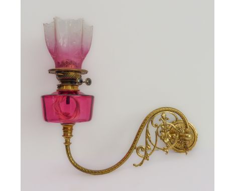 A 19th century wall-mounted brass and cranberry glass oil lamp: the six-pointed etched shade above a circular cranberry glass