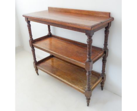 A late 19th/early 20th century three-tier oak buffet: galleried top above turned annulated supports and short turned feet ter