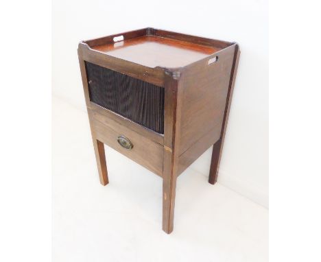 A late 18th century tray-top mahogany commode: two pierced carrying handles above a tambour front and drawer below, raised on