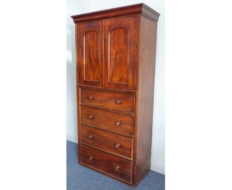 A mid 19th century mahogany cabinet on chest: the cushion moulded cornice above two arched panelled doors opening to reveal a