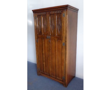 A good reproduction oak two-door wardrobe of slim proportions and good colour: the doors with arcading above and carved lozen