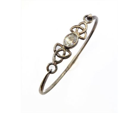 A silver bangle mounted with a central horizontal hand-cut white stone flanked by pierced Celtic style mounts