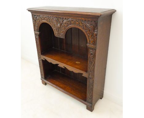 A fine quality solid oak reproduction open bookcase: the thumbnail moulded top above double arcading carved with stylised fol