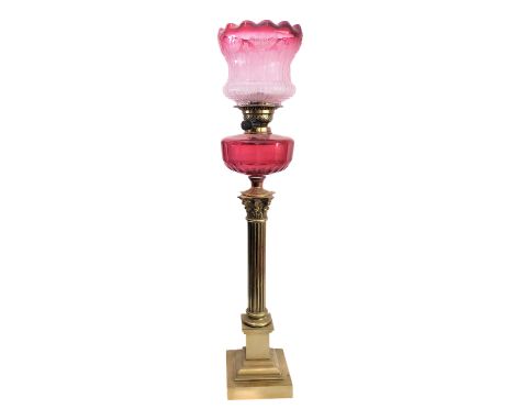 A 19th century brass and cranberry glass oil lamp: the crimped-top glass shade etched with flowers above a faceted glass rese