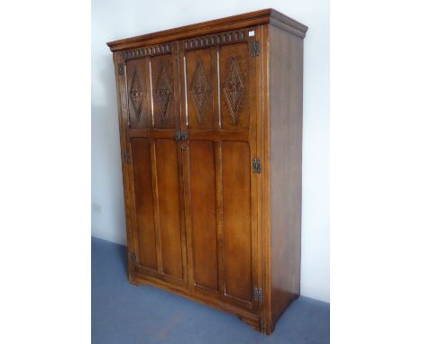 A good reproduction oak two-door wardrobe of slim proportions and good colour: the doors with arcading above and carved lozen