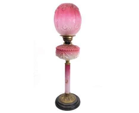 A 19th century brass, cranberry and opaline glass mounted oil lamp with ovoid cranberry-style shade and the reservoir decorat