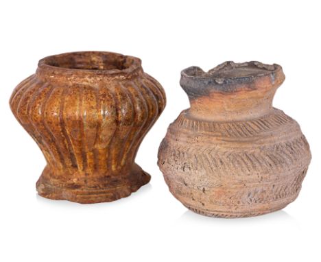 TWO EARLY SOUTHEAST ASIAN POTTERY JARS
One of fluted baluster shape with amber coloured glaze over a terracotta body; the oth
