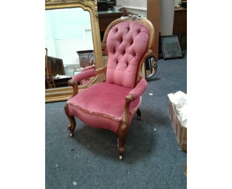 the carved walnut frame supporting a pink button upholstered back raised above an open seat with padded armrests, all support