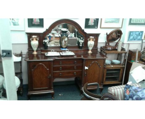 the arched mirror back with shaped display shelf resting on an inverted breakfront base with three drawers flanked by a pair 