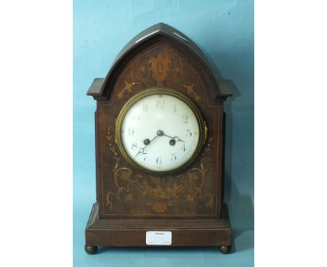 An Edwardian inlaid mahogany mantel clock, the lancet-shaped case inlaid with foliate marquetry, on brass ball feet, the conv