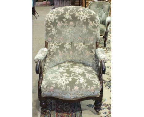 A Victorian mahogany button-back salon chair with padded arms, on turned front legs with castors.