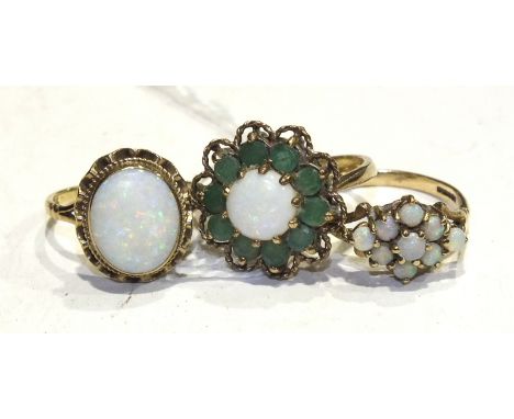 An emerald and opal cluster ring in 9ct gold mount, size K½, an opal ring with wavy mount, size L and an opal cluster ring, s