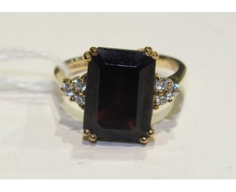 A 9ct gold ring set a large trap-cut garnet between white-stone-set shoulders, in 9ct gold mount, size P½, 5.5g.